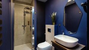 A modern bathroom with a glass-enclosed shower, a white toilet, and a large oval sink. - Yuko Residence (Jasło)