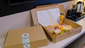 Two cardboard boxes with food items on a table, a kettle, and a television in the background. - Yuko Residence (Jasło)