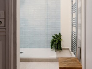 Ein Badezimmer mit einer Badewanne, einer Topfpflanze und einer hölzernen Bank.