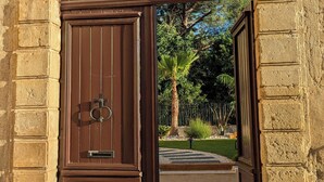 A large, brown wooden door with a metal handle, set in a stone wall with a number '1' sign.