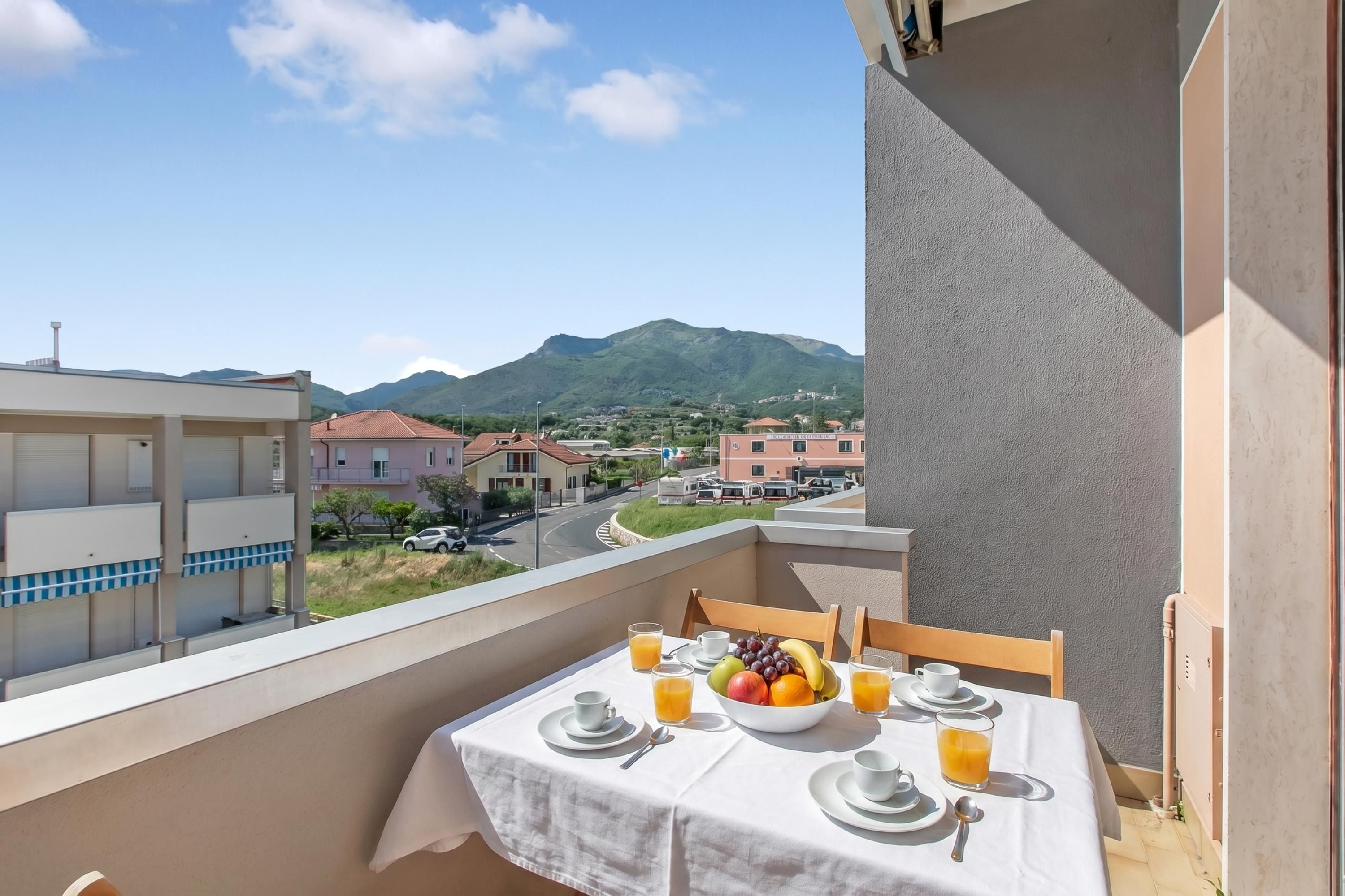 Ein Balkon mit einem für das Frühstück gedeckten Tisch, einer Obstschale und Gläsern Orangensaft.