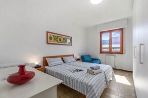 A bedroom with a bed, a nightstand, a red vase, a window with a view, and a painting on the wall. - Appartamento Magenta - Apartment With Sunny Balcony (Loano)