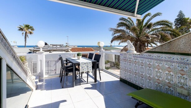 A balcony with a table and chairs, a green bench, and a patterned wall. - Charming Bungalow With Ocean Views in Roquetas de Mar (Roquetas de Mar)
