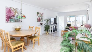 A spacious living room with a dining area, a TV, and a balcony with a view. - Charming Bungalow With Ocean Views in Roquetas de Mar (Roquetas de Mar)