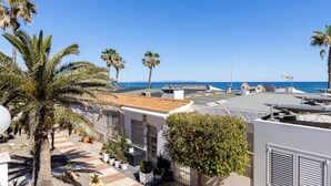 A rooftop terrace with palm trees, a view of the sea, and a building with a tiled roof. - Charming Bungalow With Ocean Views in Roquetas de Mar (Roquetas de Mar)