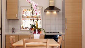 A modern kitchen with wooden cabinets, a dining table with chairs, and a decorative orchid vase. - CrauNari Agritourism and Educational Company (Modica)