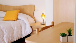A hotel room with a bed, a bedside table with a lamp, a small table with two potted plants, and a wooden headboard. - CrauNari Agritourism and Educational Company (Modica)