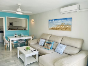 A modern living room with a sofa, coffee table, and dining area. - Goldküsten by At Home Costa del Sol (Torrox)
