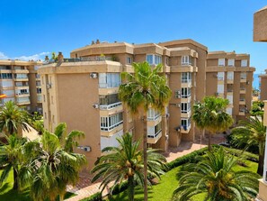 A multi-story hotel with balconies, air conditioning units, and palm trees. - Goldküsten by At Home Costa del Sol (Torrox)