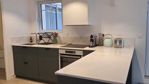 A compact kitchen with a built-in oven, a sink, and a window above the counter. - Villa Mandarine (Arcachon)