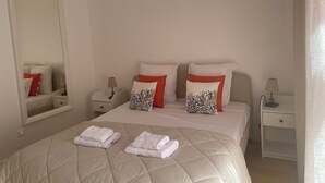 A hotel room with a bed, a nightstand, a lamp, a mirror, and a window. - Villa Mandarine (Arcachon)