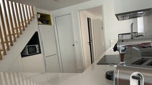 A modern kitchen with a built-in microwave, a toaster, and a stainless steel range hood. - Villa Mandarine (Arcachon)