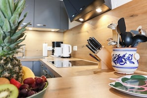 Eine moderne Küche mit Holzarbeitsplatte, einer Obstschale, einer Kaffeemaschine und einem dekorativen Keramiktopf.