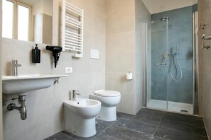 A modern bathroom with a sink, bidet, toilet, and glass-enclosed shower. - Camera Superior   Piazza Bologna (Roma)