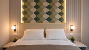 Quarto de hotel com uma cama grande, duas mesas de cabeceira, luminária fixada na parede e um painel decorativo.