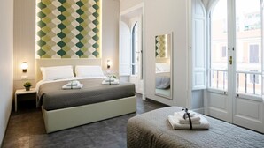Quarto de hotel moderno com uma cama grande, mesas de cabeceira, um espelho e vista da cidade através de janelas amplas.