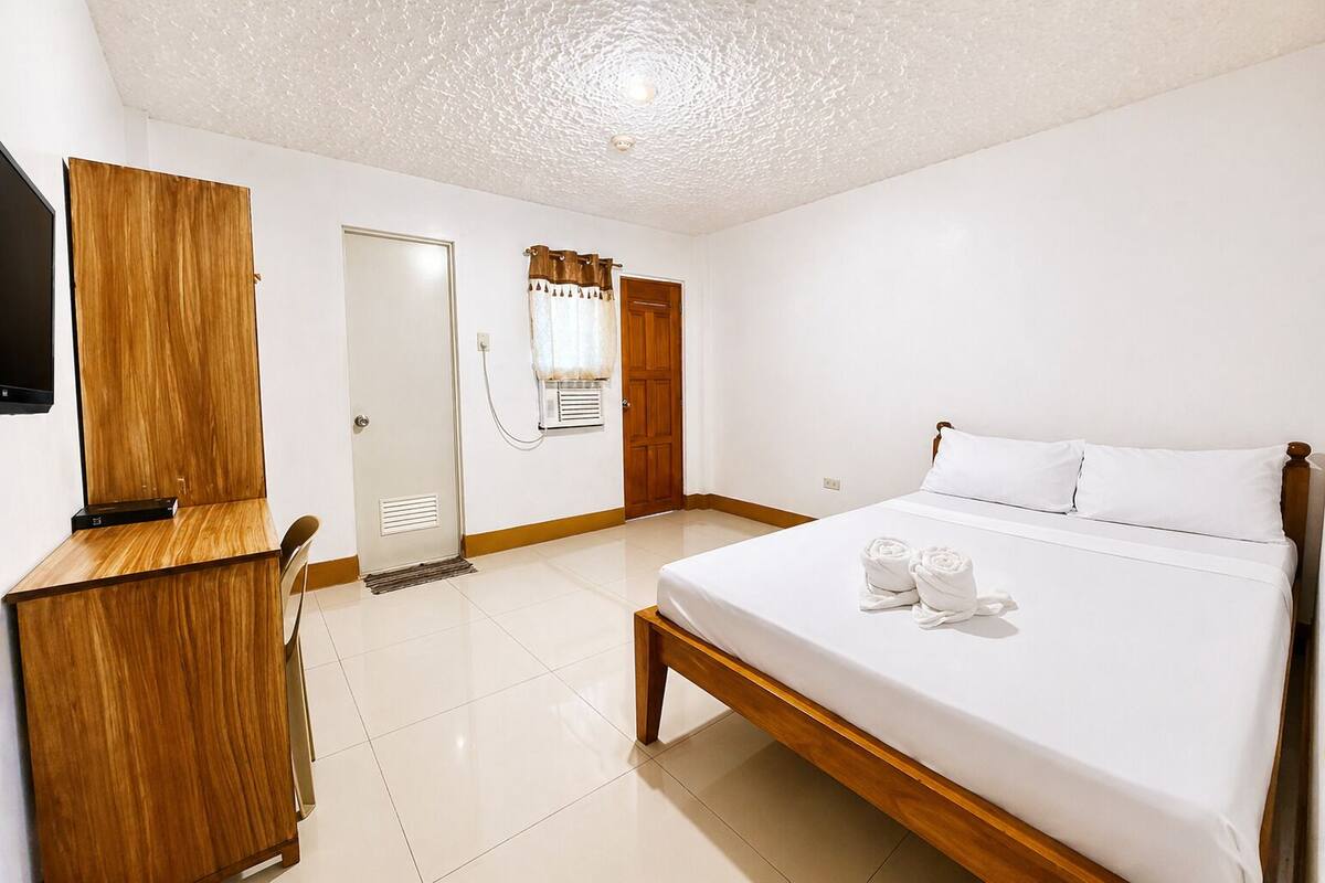 A hotel room with a bed, a desk, a television, and a shower.