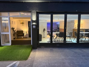 A modern building with a glass entrance, a number 399 sign, and a dining area with tables and chairs. - 399 Prom - Blackpool Hotel (Blackpool)