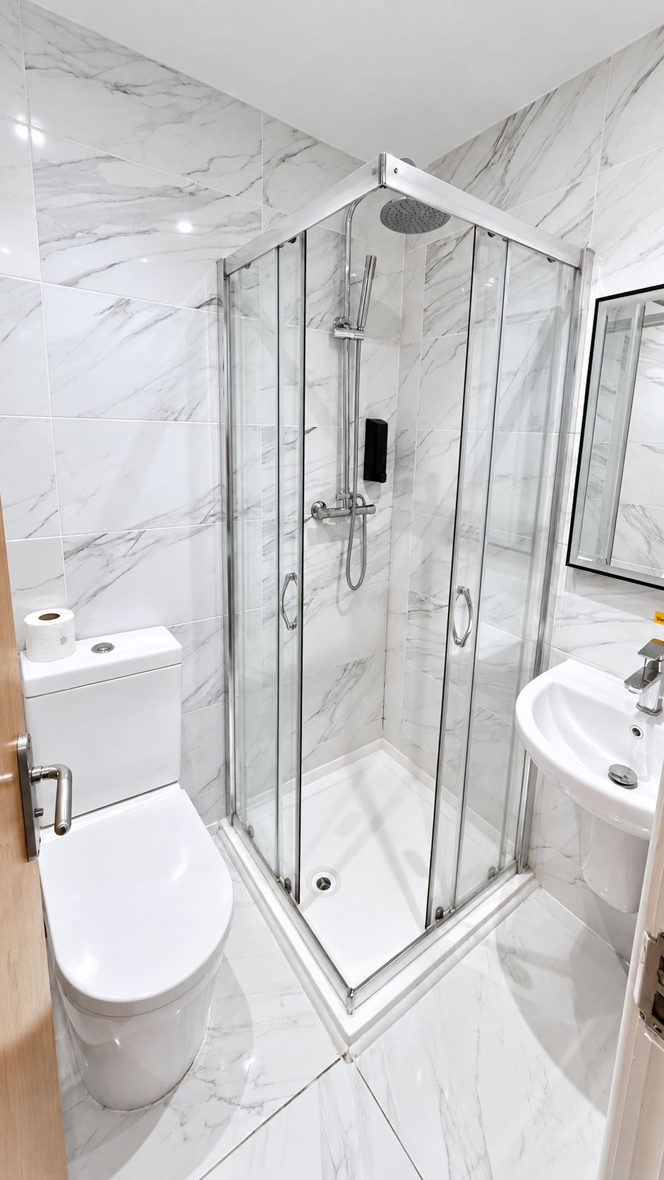 A modern bathroom with a glass-enclosed shower, a toilet, and a sink.