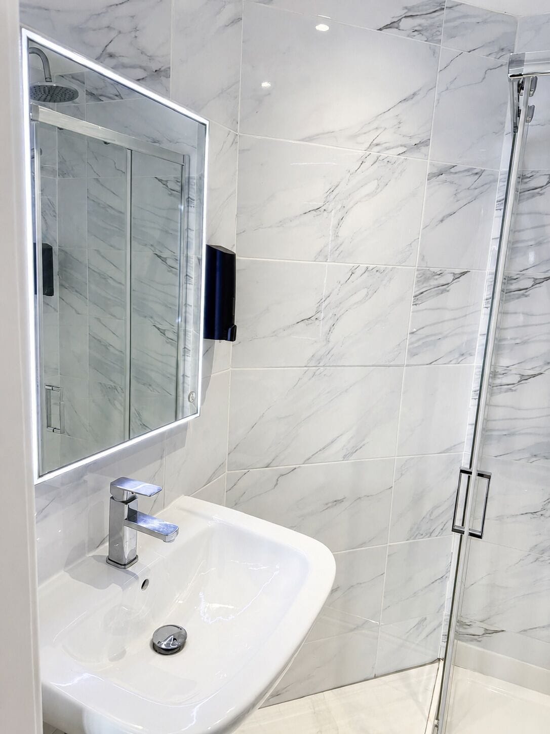 A modern bathroom with a white sink, a mirror, and a shower enclosure.