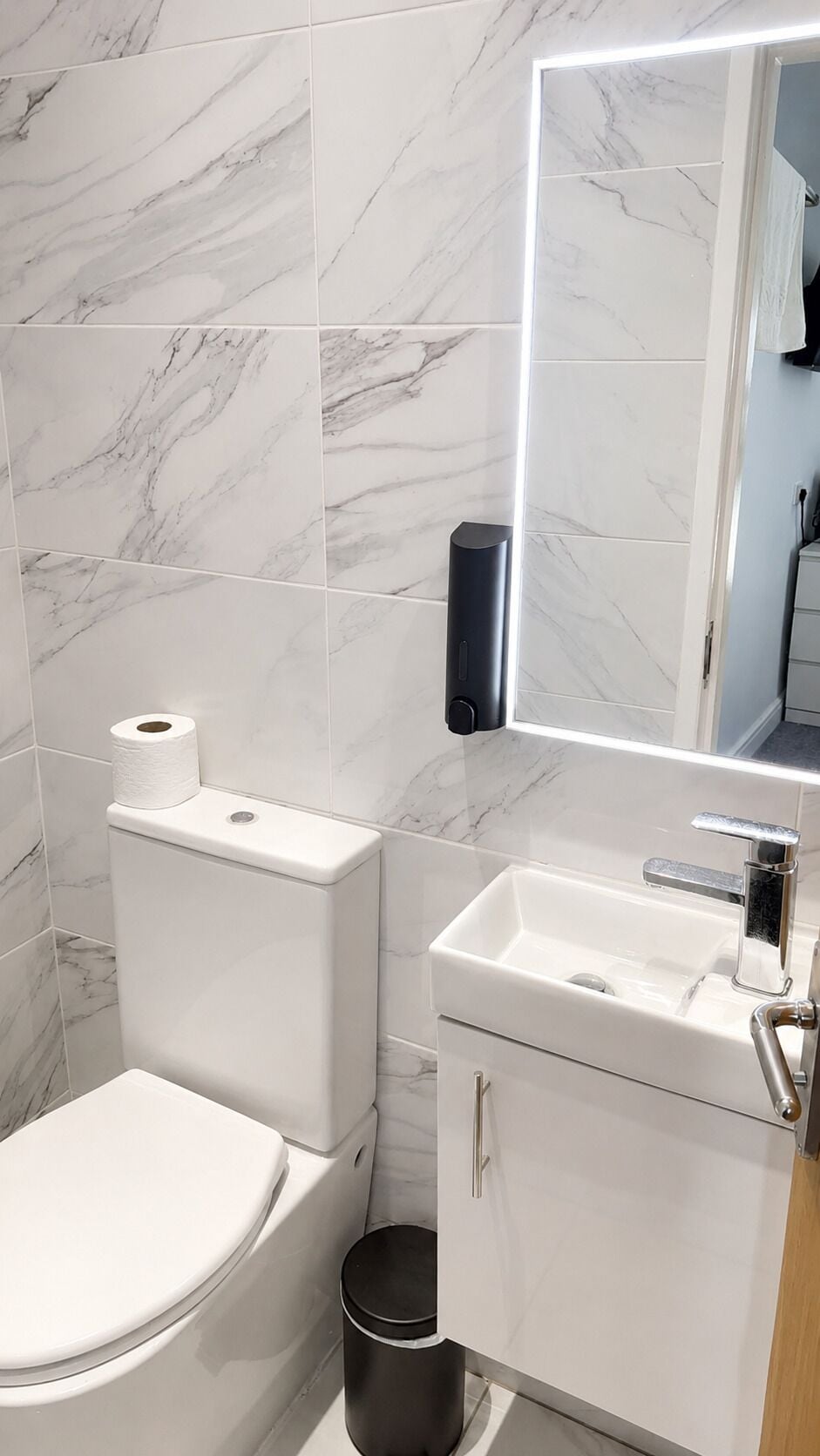 A bathroom with a toilet, a sink, and a mirror.