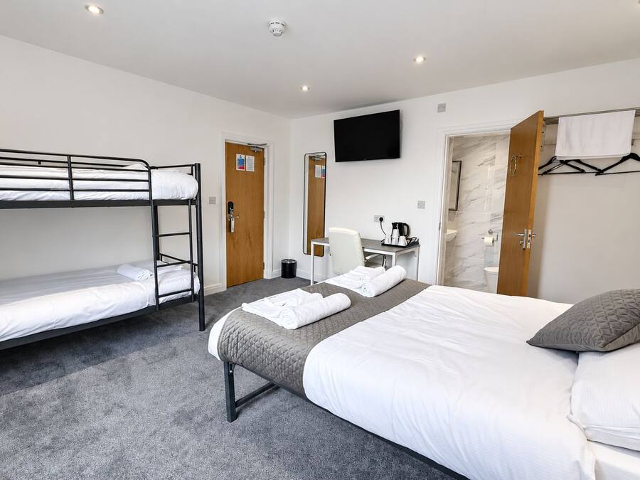 A hotel room with bunk beds, a desk, a television, and a bathroom.