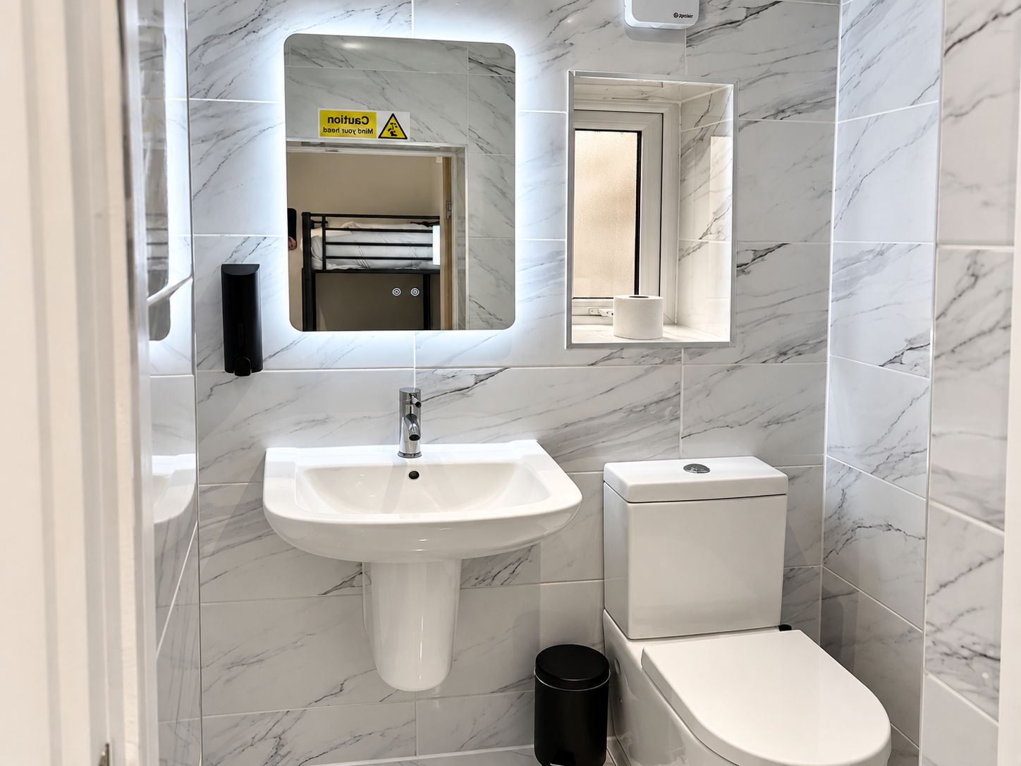 Un baño con lavabo, inodoro y espejo.