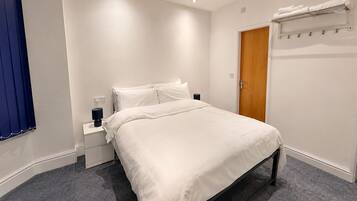 A neatly arranged bedroom with a bed, bedside table, and a wardrobe.