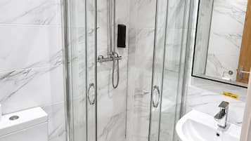 A modern bathroom with a glass-enclosed shower, a white toilet, and a sink with a mirror.