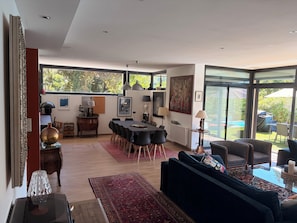 Ein modernes Wohnzimmer mit einer großen Couch, einem Essbereich mit Stühlen und Blick ins Freie.
