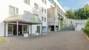 Un bâtiment moderne doté d’une entrée couverte portant l’inscription « espace vert », d’un chemin pavé et d’une structure en béton agr émentée de végétation.