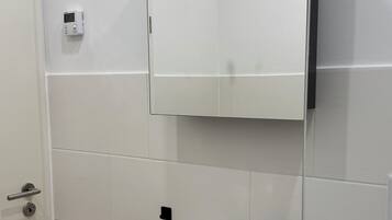 Un baño con un lavamanos blanco, un grifo negro y un espejo encima.