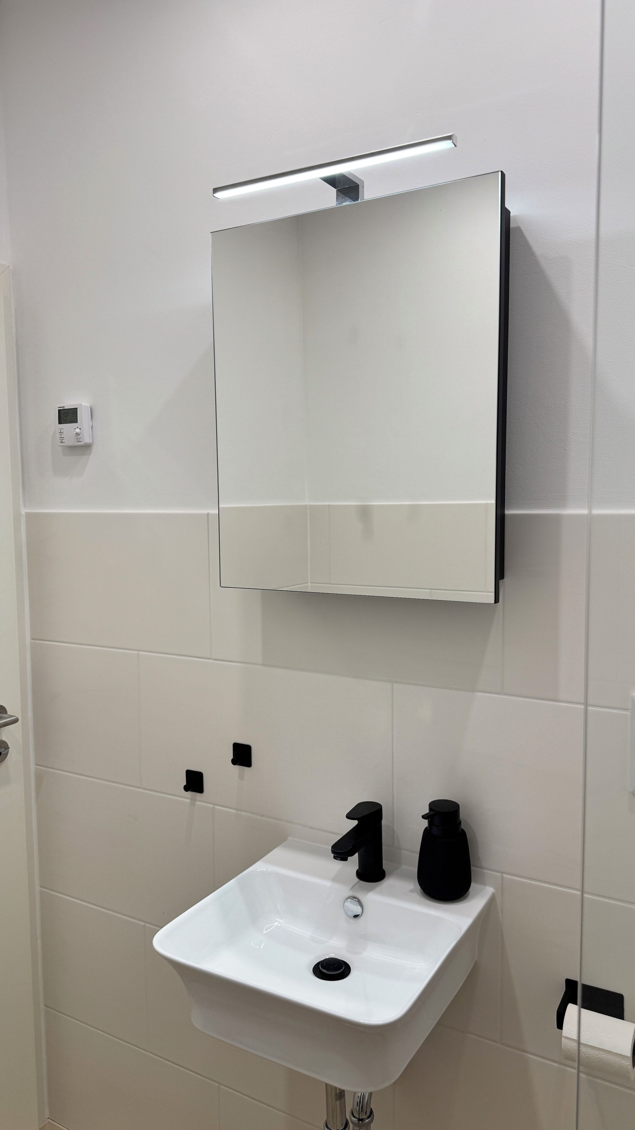 A bathroom with a white sink, black faucet, and a mirror above it.