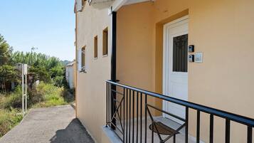 A building with a balcony, a door with a keypad, and a small window.