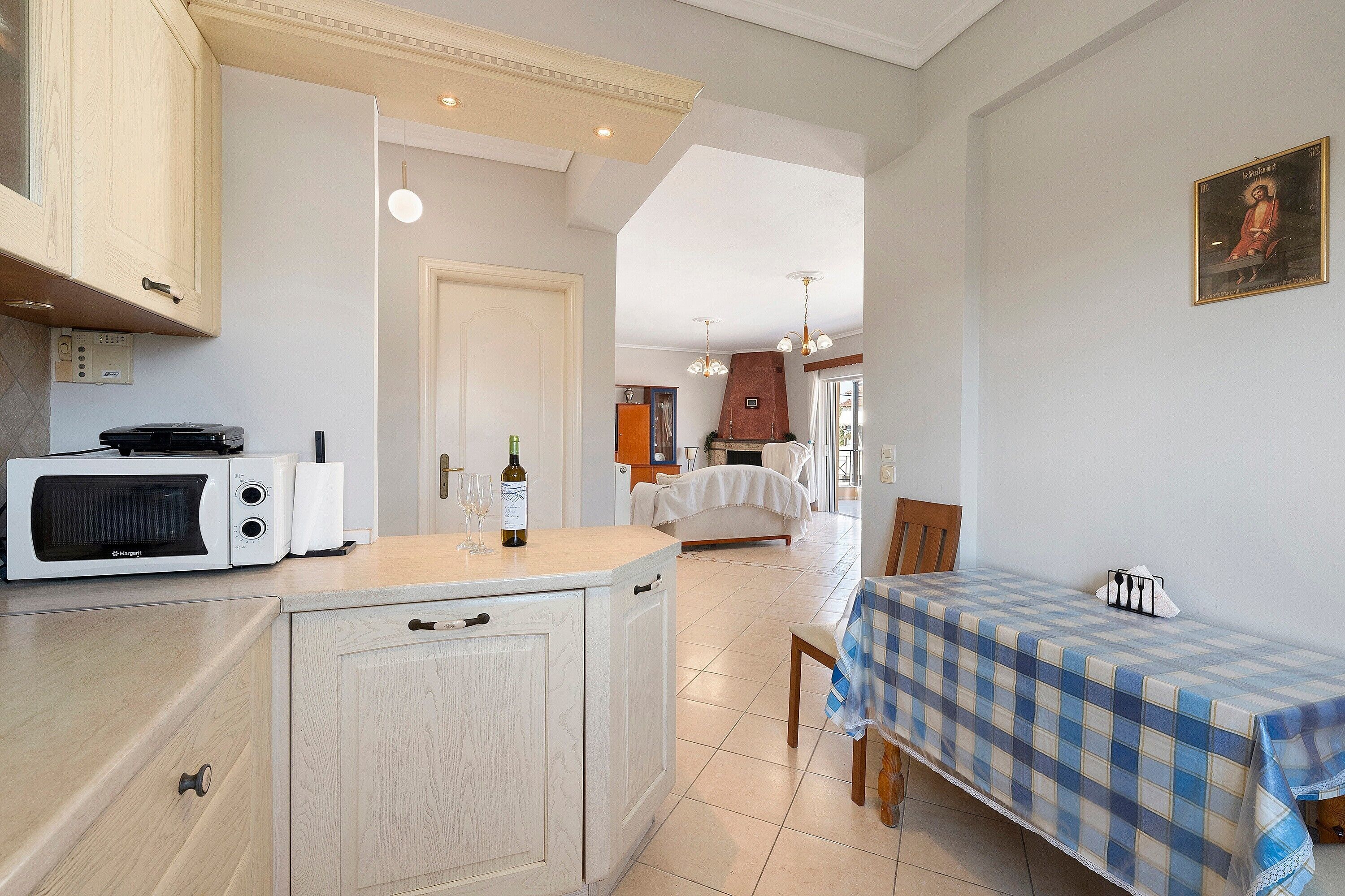 A compact kitchen with a microwave, a wine bottle, and glasses on the counter.