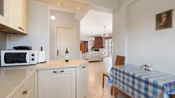 A compact kitchen with a microwave, a wine bottle, and glasses on the counter.
