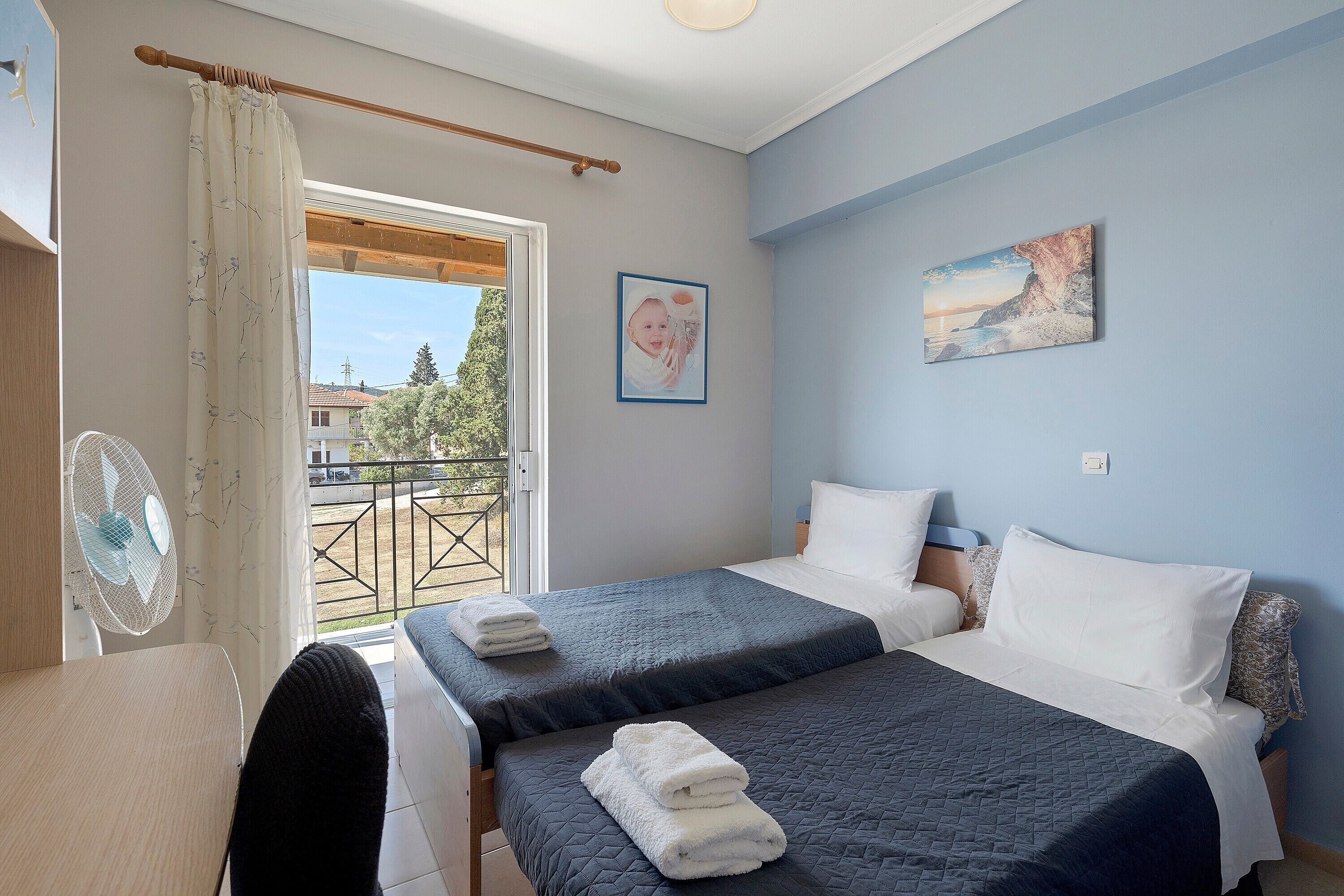 A bedroom with two beds, a view of the outside, and a painting on the wall.