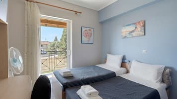 A bedroom with two beds, a view of the outside, and a painting on the wall.
