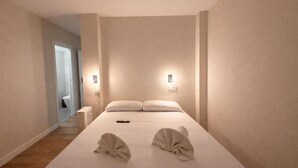 Una habitación de hotel con una cama grande, dos lámparas de noche, un control remoto y una cama bien tendida con toallas.