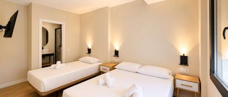 A hotel room with two beds, bedside tables, wall-mounted lamps, and a mirror.