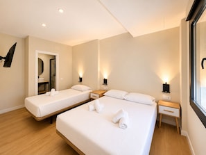 Una habitación de hotel con dos camas, mesitas de noche, lámparas de pared y un espejo.