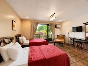 Une chambre d’hôtel avec deux lits, un bureau, une chaise, une télévision et un balcon avec des rideaux.