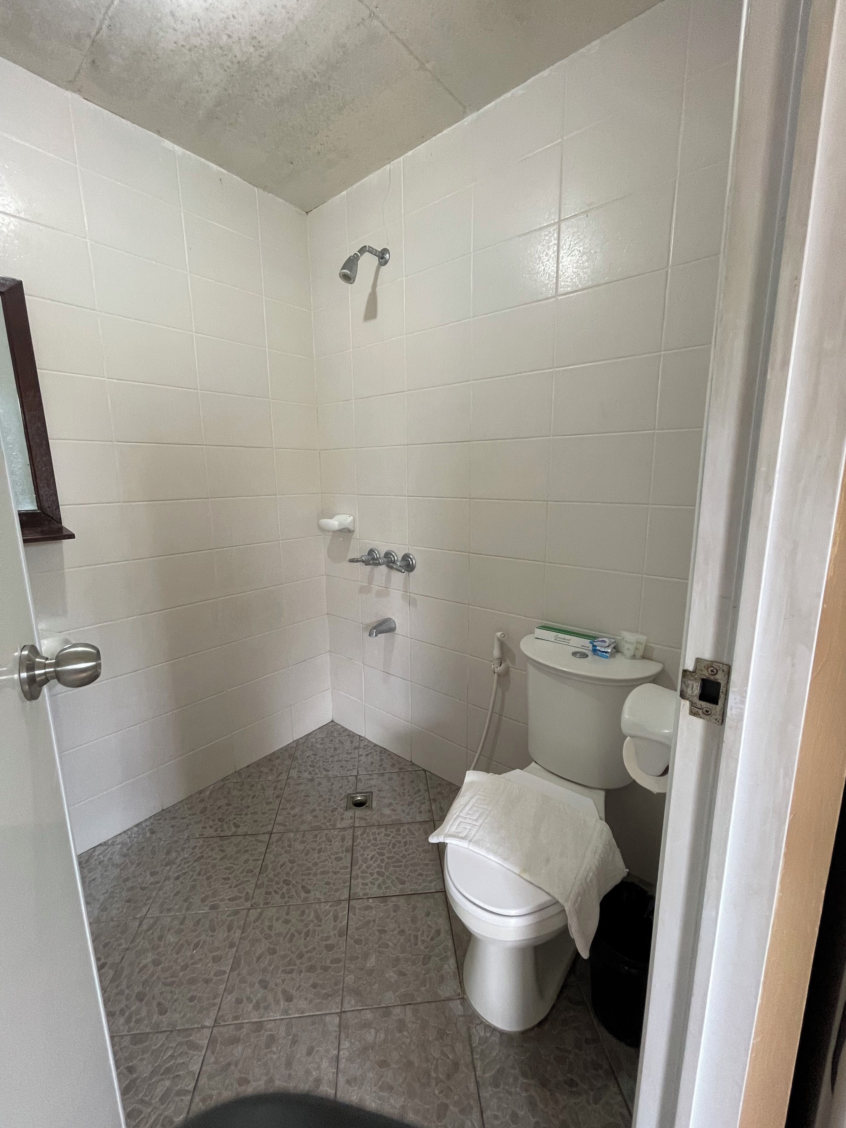 A bathroom with white tiles, a shower, a toilet, and a sink.