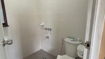 A bathroom with white tiles, a shower, a toilet, and a sink.