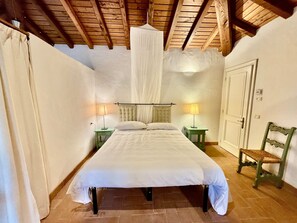 A bedroom with a bed, two bedside tables with lamps, a wooden bench, and a door. - Pizzaz Abruzzo Mountain Family Retreat Romantic Get-away or Unique Event Venue (Torre de' Passeri)