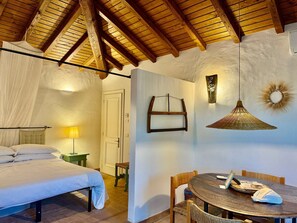 Ein Schlafzimmer mit einem Bett, einem Tisch mit Stühlen, einer Hängelampe und einer Tür.