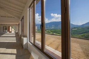 A corridor with large windows, a wooden ceiling, and a view of a valley with mountains. - Pizzaz Abruzzo Mountain Family Retreat Romantic Get-away or Unique Event Venue (Torre de' Passeri)