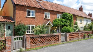 A traditional brick house with a tiled roof, a wooden gate, and a brick wall with a lattice design.