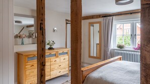 A bedroom with a wooden bed, a dresser, a mirror, and a window with curtains.