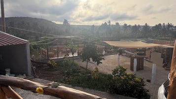 Um pátio com cerca de madeira, um pequeno edifício e vista para uma colina com palmeiras.